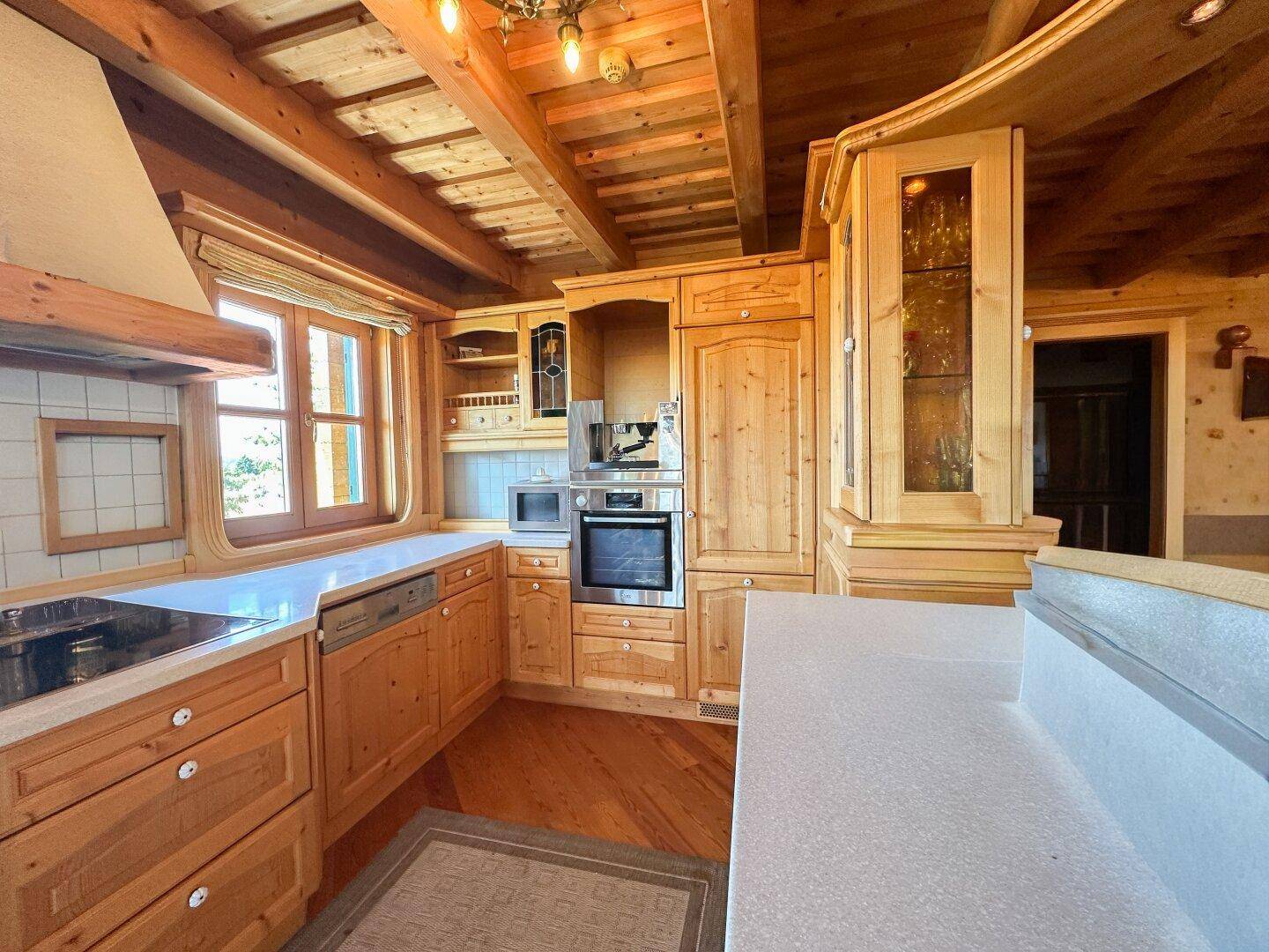 Traditionelle Holzküche mit Einbaugeräten, hellen Holzschränken und einem Fenster.