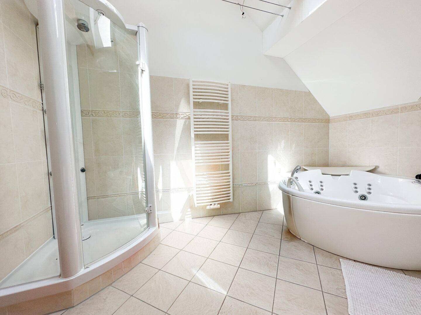 Geräumiges Badezimmer mit moderner Duschkabine, Whirlpool und beheiztem Handtuchhalter.