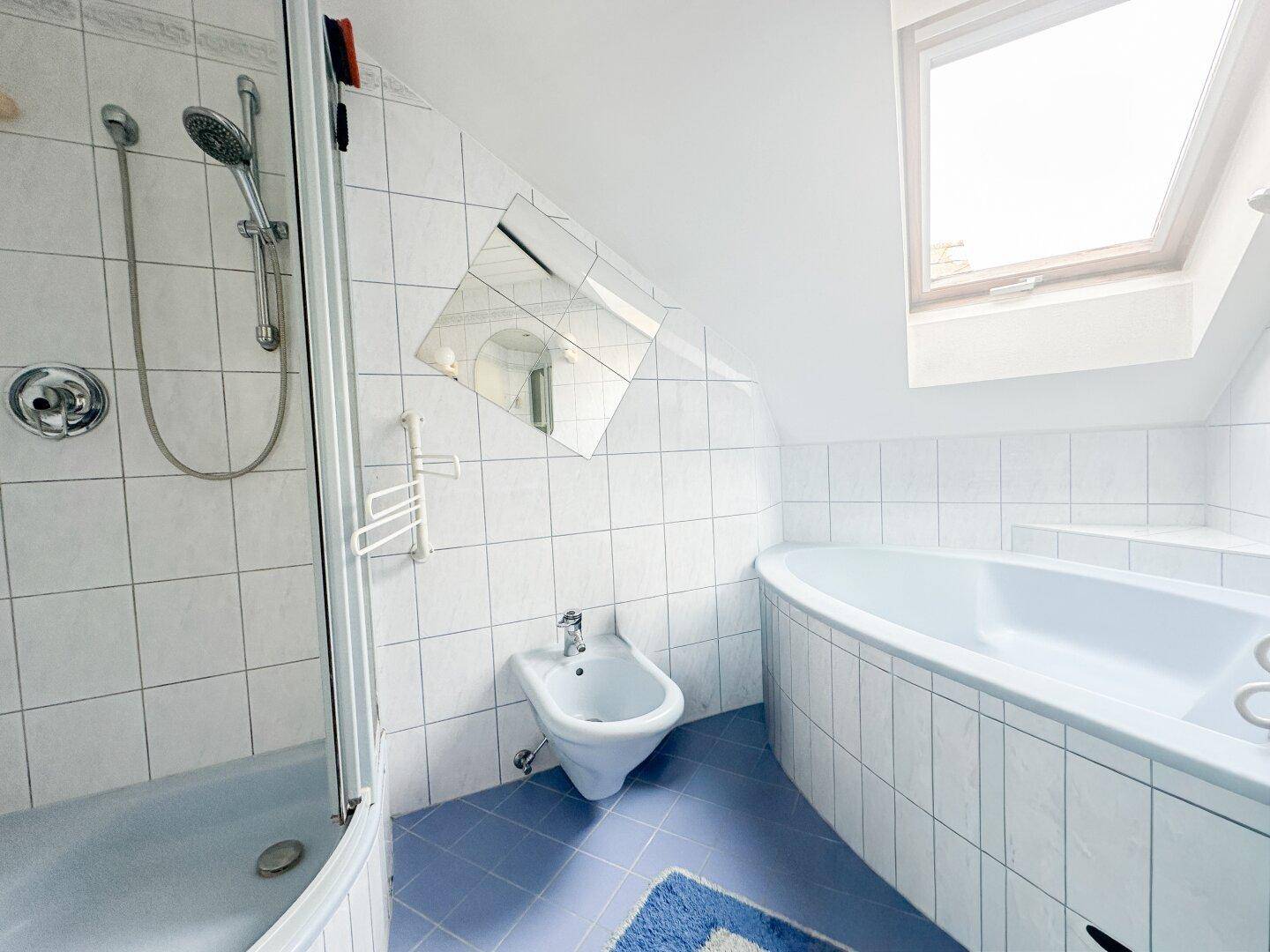 Badezimmer im 80er-Jahre-Stil mit Dusche, Bidet, Eckbadewanne und Dachfenster.