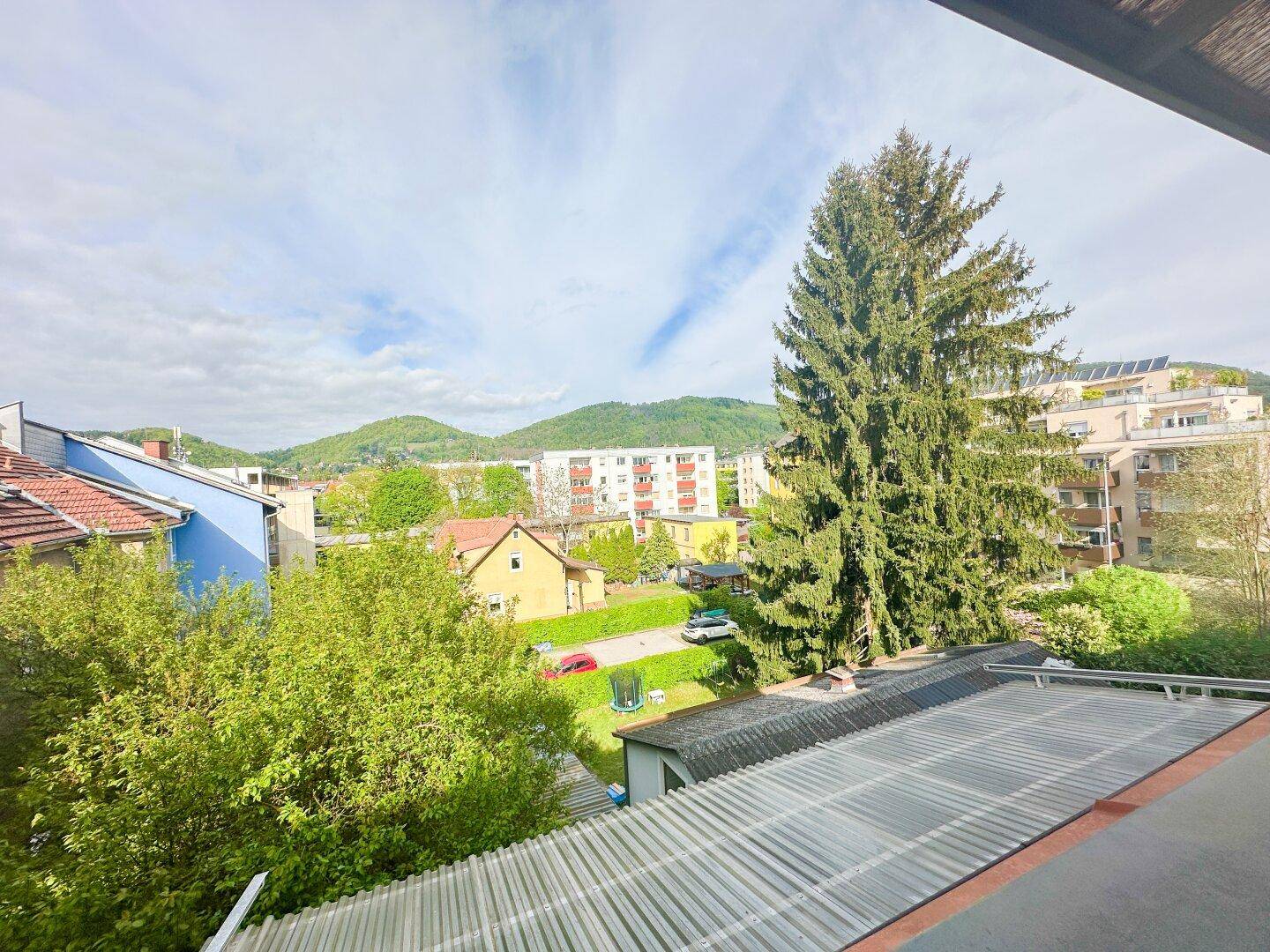 Weitblick über die Stadt und grüne Hügel von einem Balkon aus.