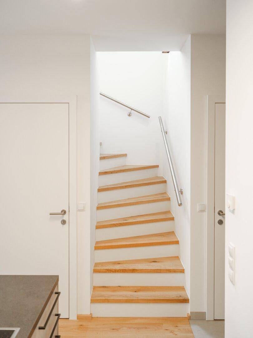 Moderne Holztreppe mit Edelstahlgeländer, die die Etagen verbindet.