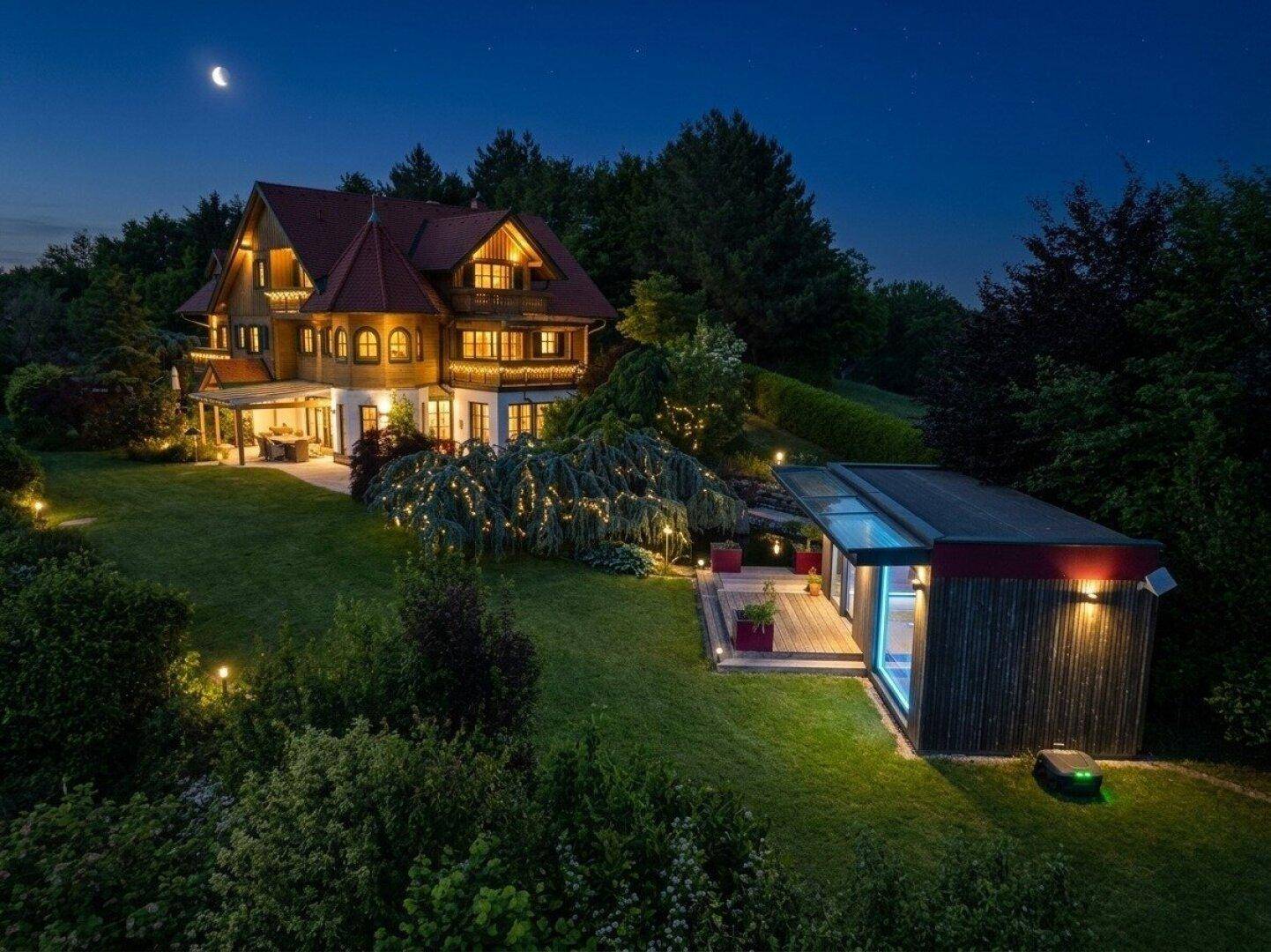 Gesamtanwesen bei Nacht mit Haupthaus, modernem Nebengebäude und weitläufigem, beleuchtetem Garten.