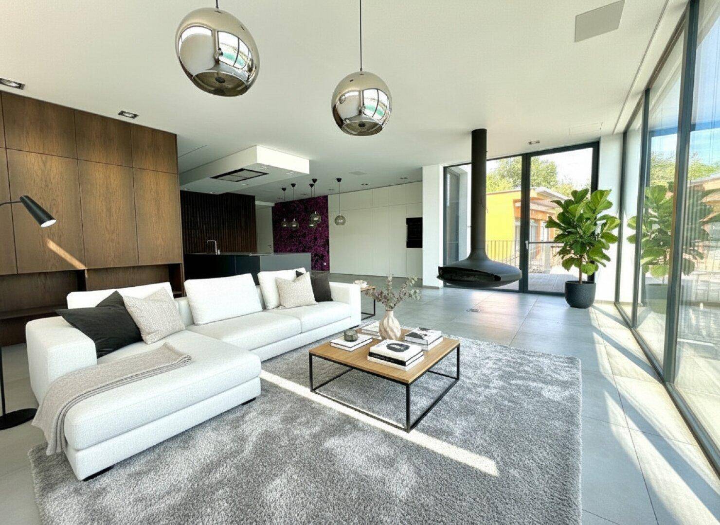 Geräumiges Wohnzimmer mit bequemer Couch, modernem Kamin und Blick auf den See.