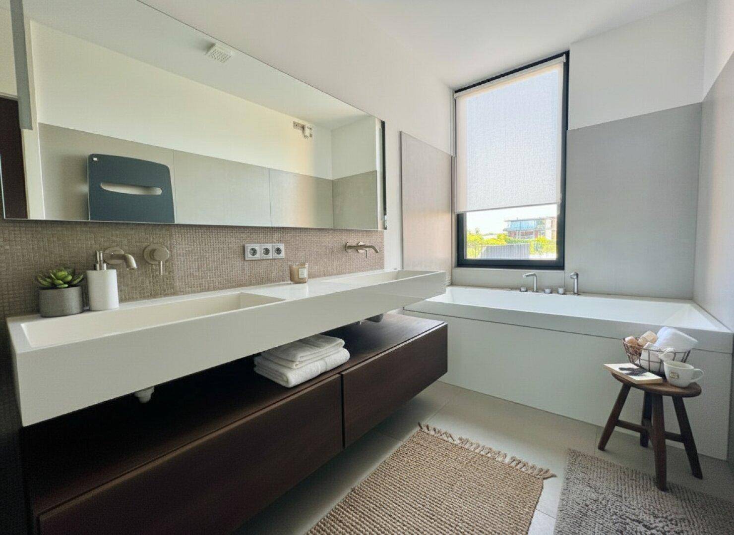 Modernes Badezimmer mit Doppelwaschbecken, Badewanne und Fenster.