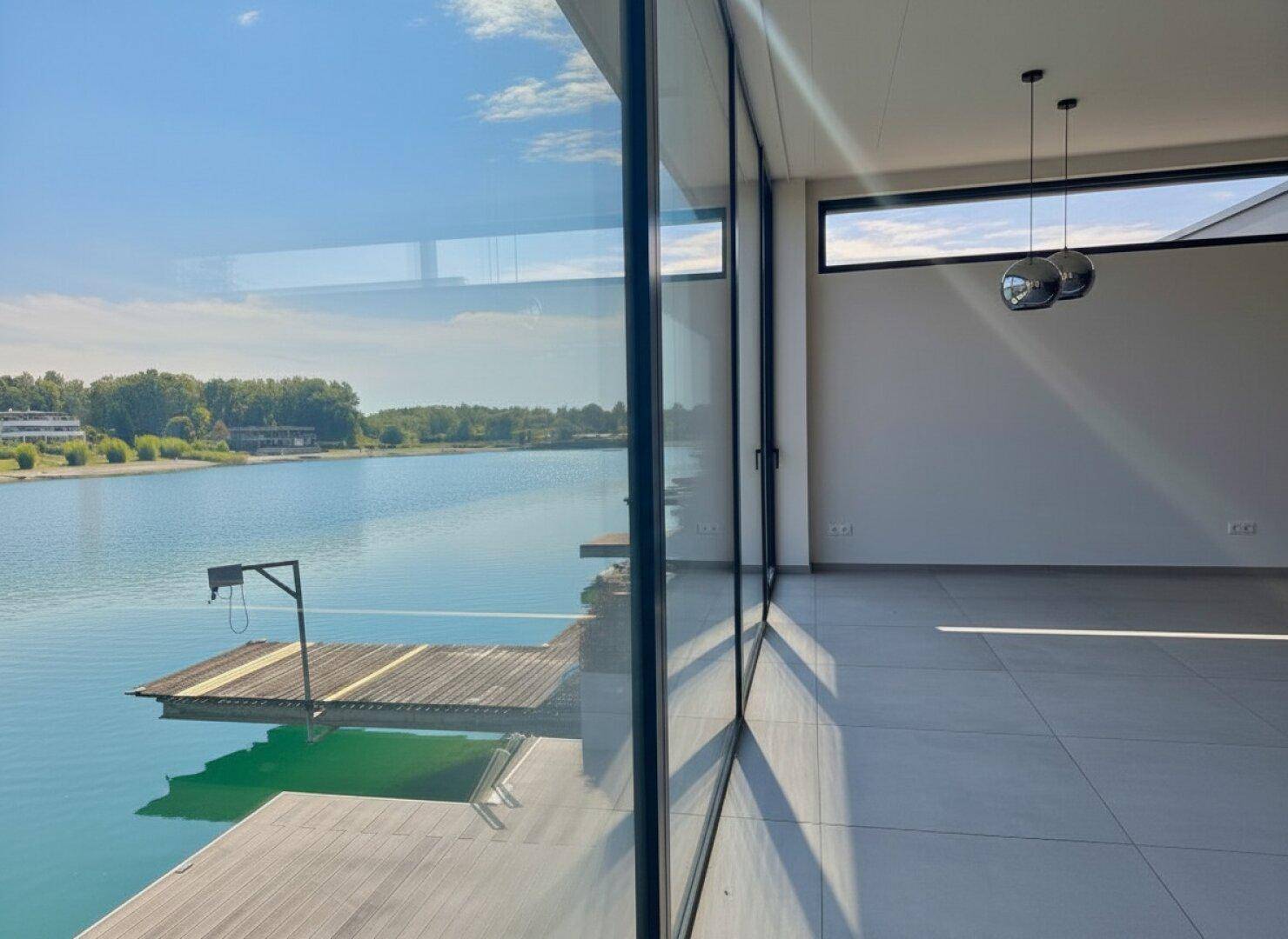 Heller Innenraum mit großen Fenstern und weitem Blick auf den See.