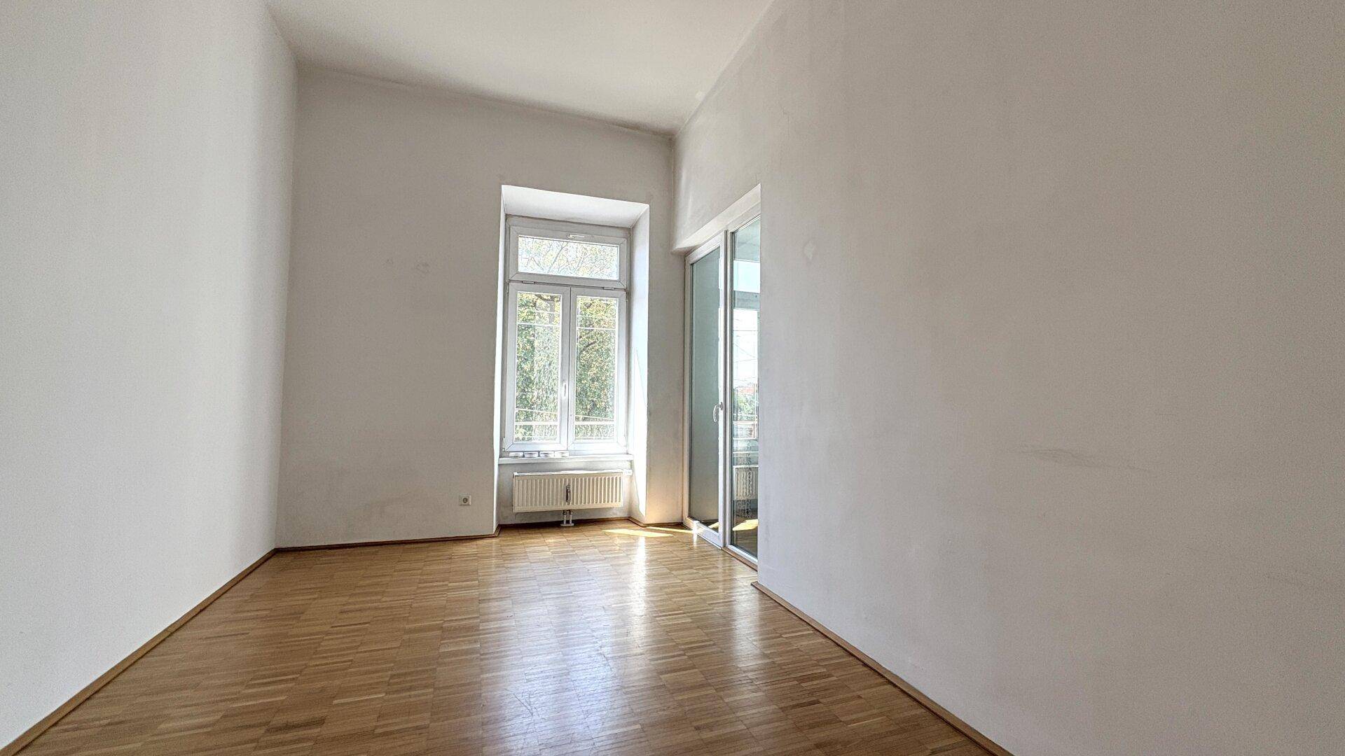 Heller Raum mit Parkettboden und einer großen Glasschiebetür, die viel Licht in den Wohnbereich bringt.