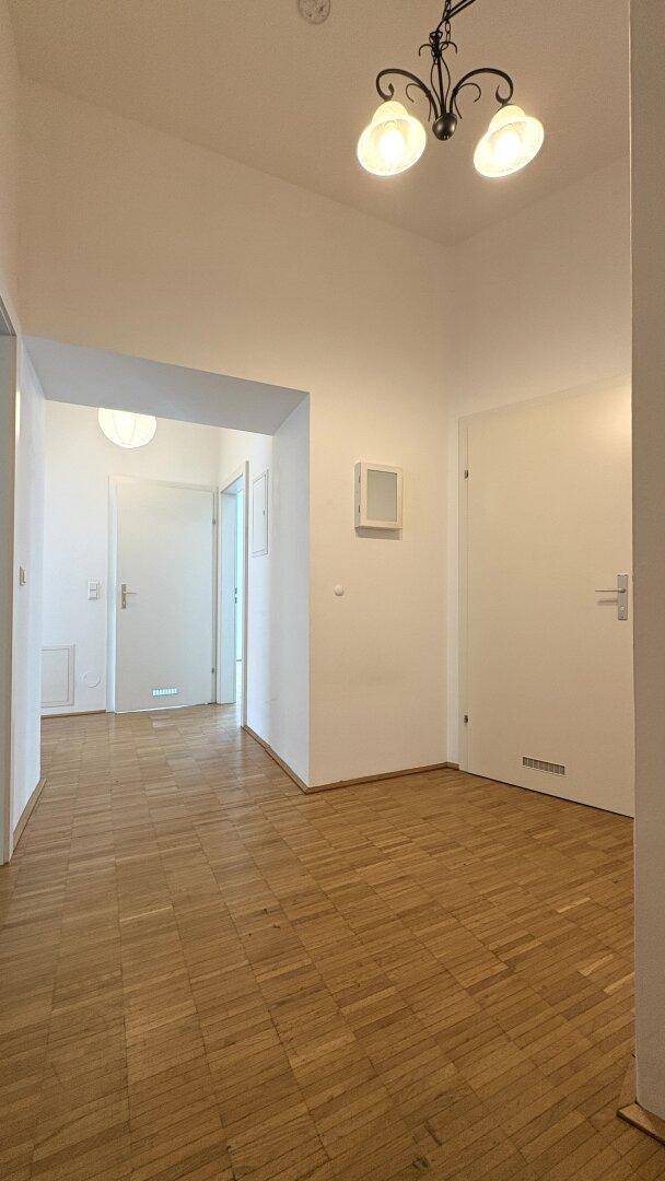 Heller Flur mit Parkettboden und mehreren Türen, die zu verschiedenen Räumen führen.