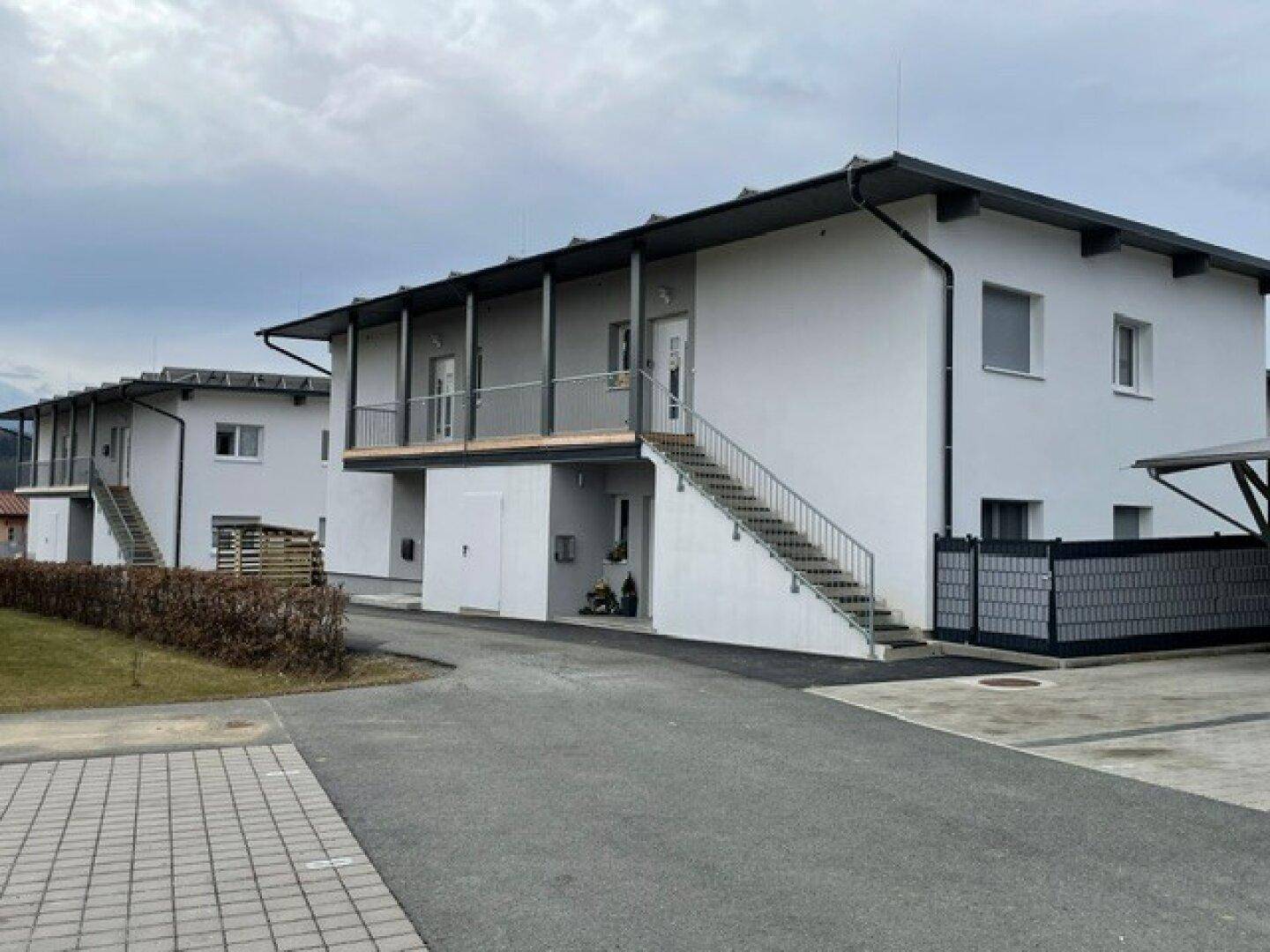 Moderne Wohnanlage mit mehreren Einheiten, Außentreppen und Carports in einer ländlichen Umgebung.