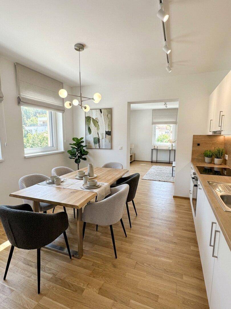 Offene Küche mit Essbereich und Holzboden, die in den hellen Wohnbereich übergeht.