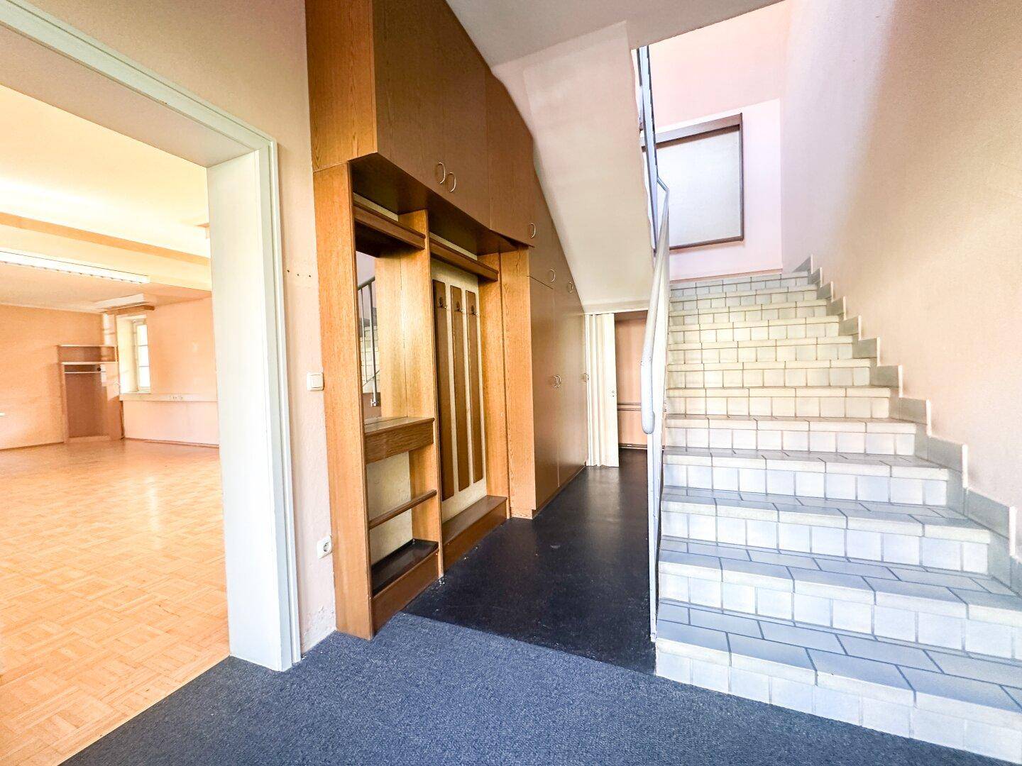 Ein Eingangsbereich mit einer gefliesten Treppe und einem Aufzug, der zu weiteren Räumen führt.