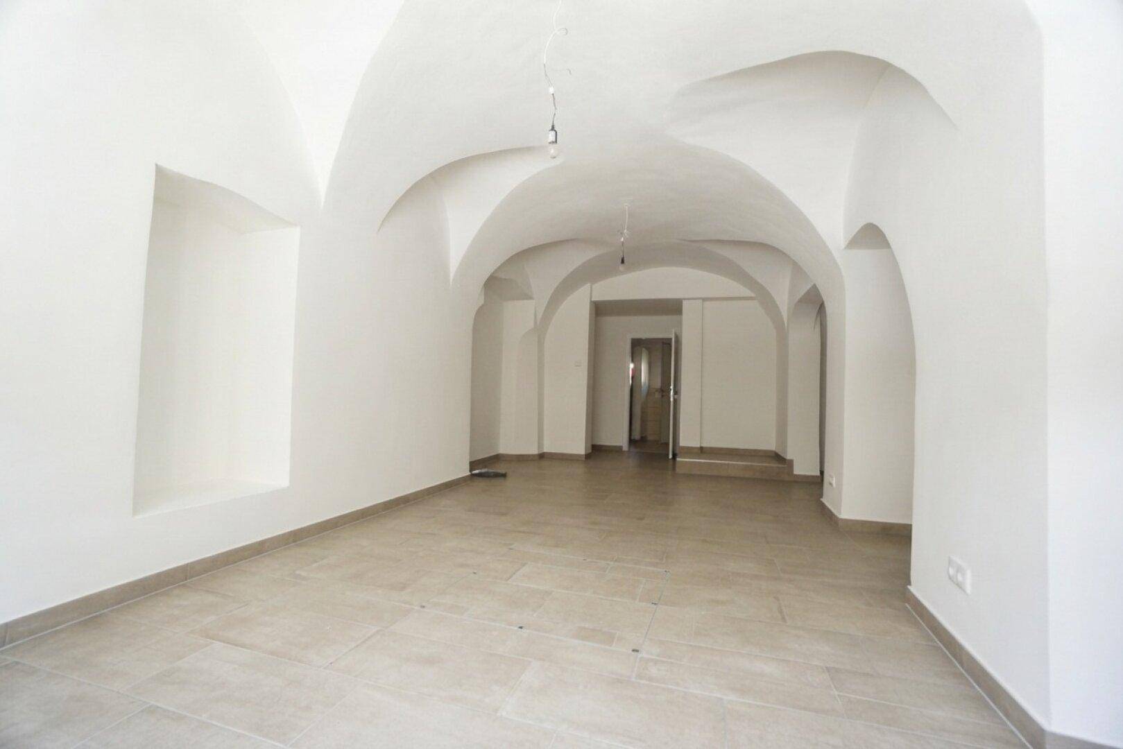 Weiterer Blick in den weitläufigen Gewerberaum mit Gewölbedecken und hellem Fliesenboden.