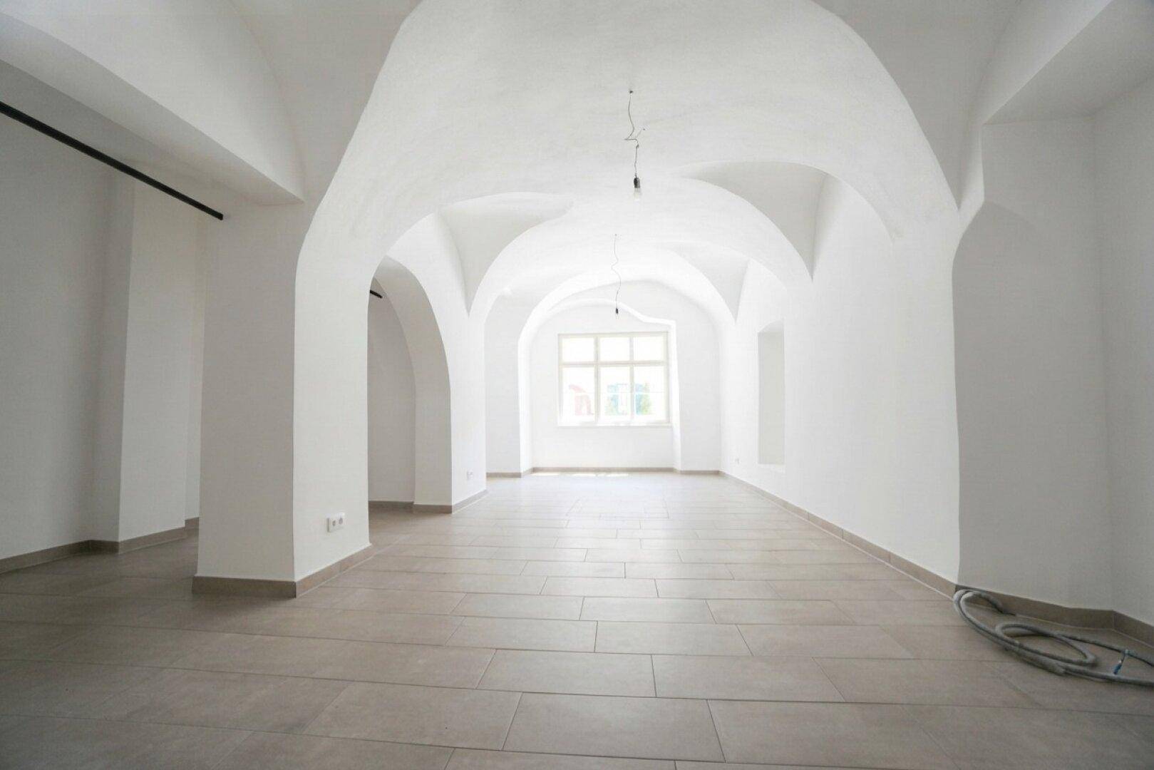 Großer, leerer Gewerberaum mit beeindruckenden Gewölbedecken und Fliesenboden.