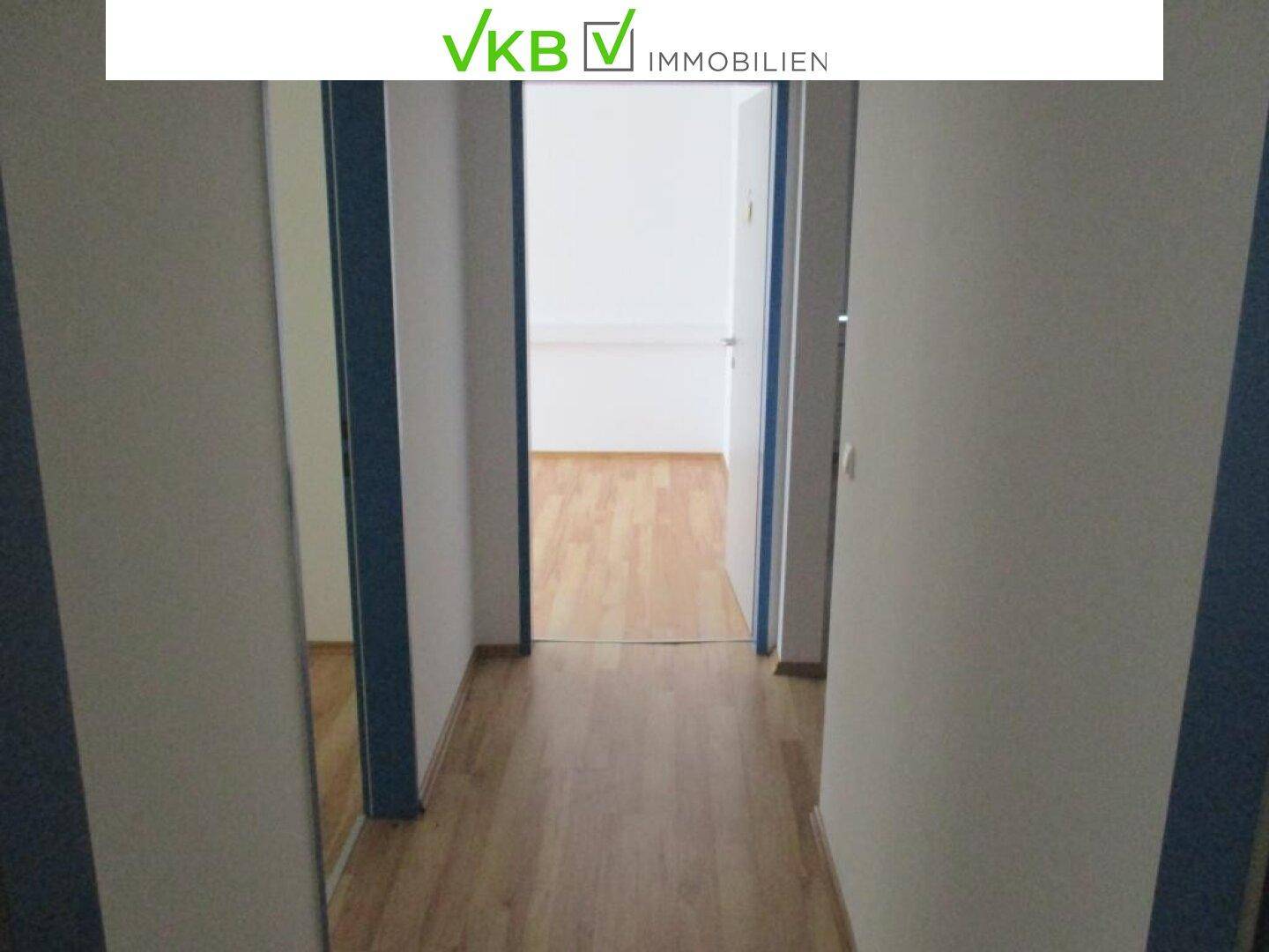 Langer, heller Korridor mit Holzboden, der zu weiteren Büroräumen führt.