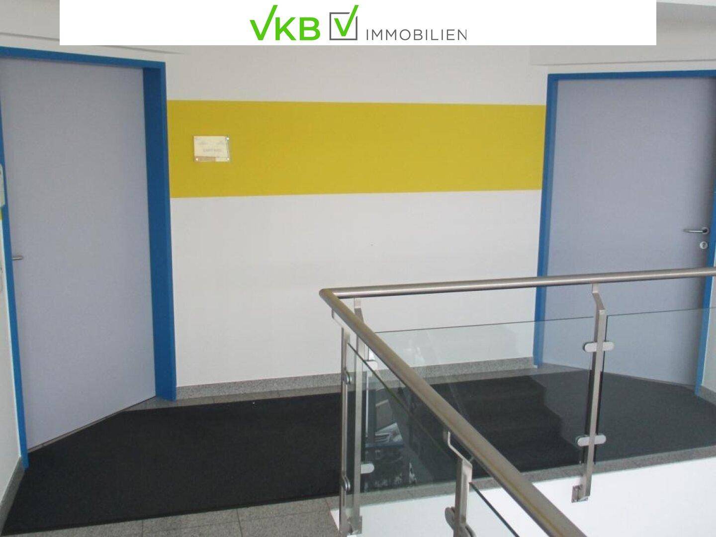 Heller Flur im Obergeschoss mit gelbem Akzentstreifen an der Wand und modernem Glasgeländer.