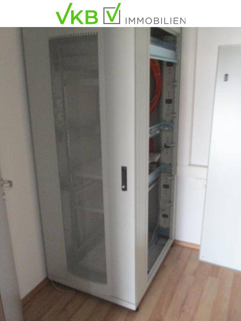 Serverraum mit einem leeren Serverschrank und Holzboden, bereit für die Installation.