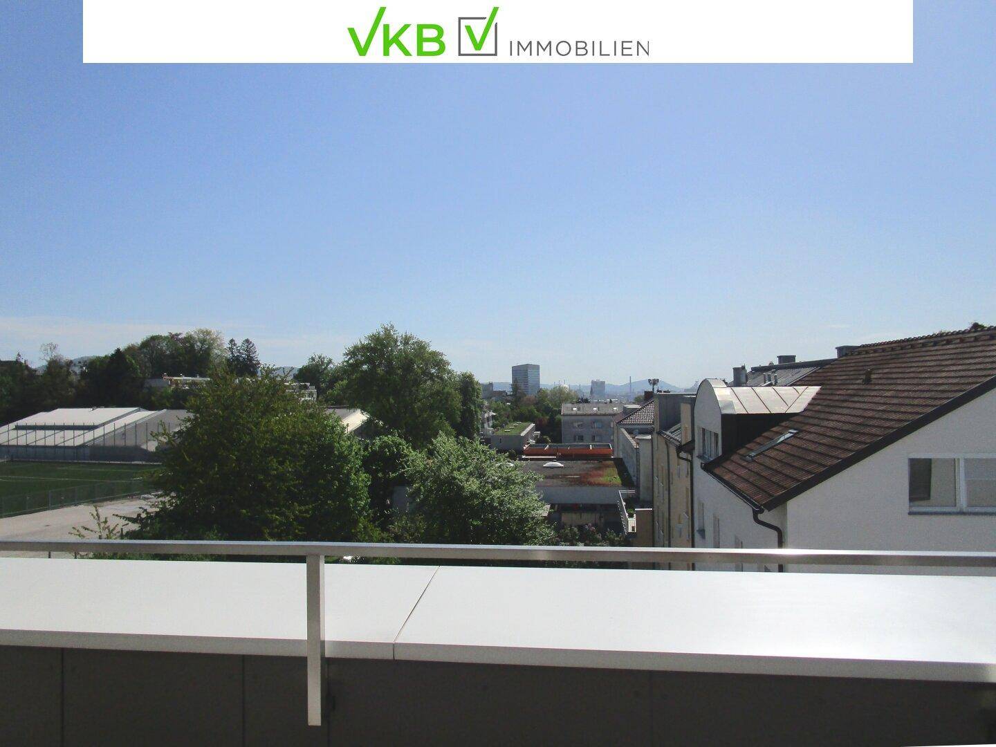 Weitläufiger Ausblick von der Terrasse über die Dächer der Stadt und die grüne Umgebung.