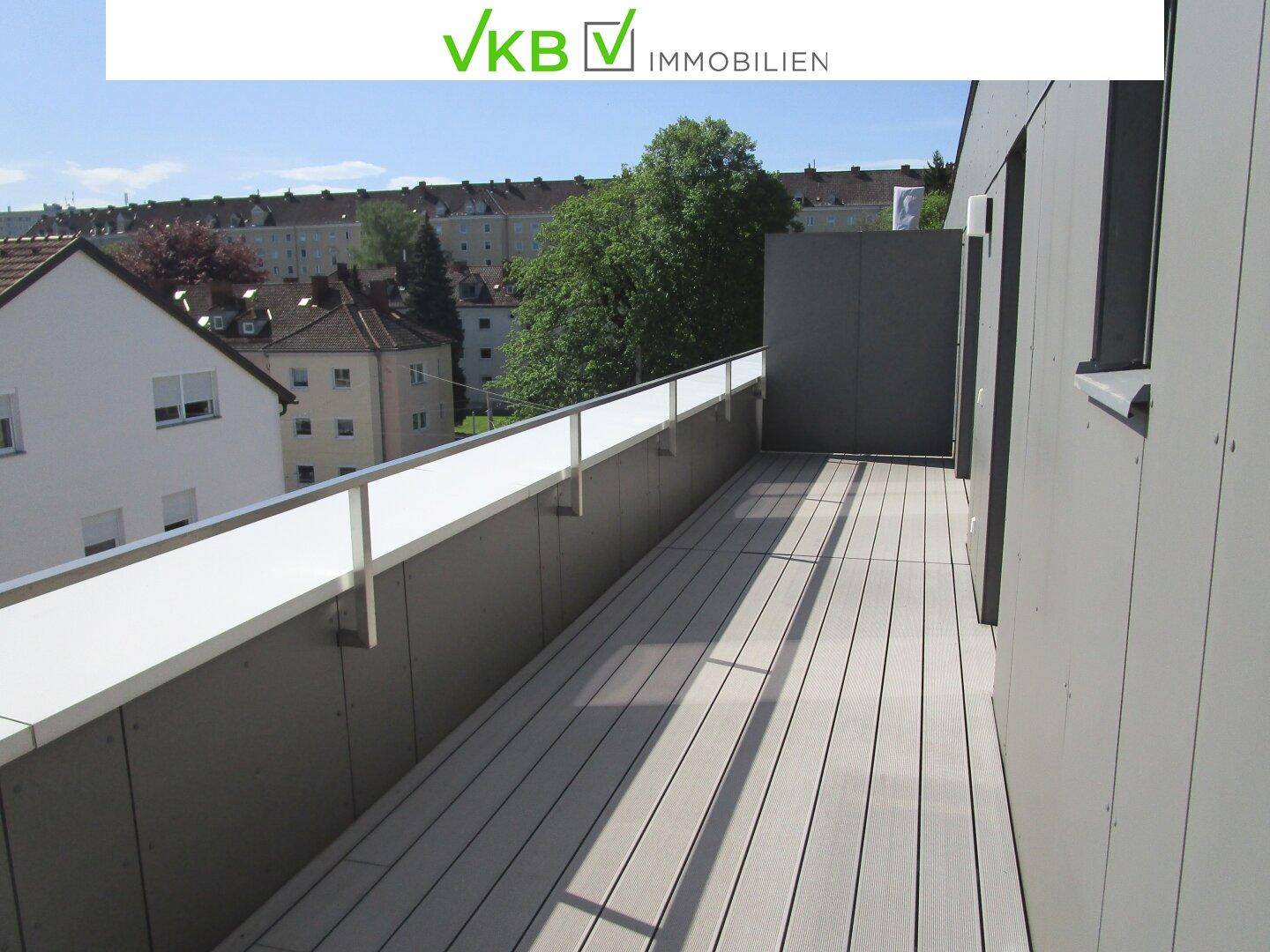 Geräumige Terrasse mit modernen Holzdielen und einem Geländer, das einen weiten Blick ermöglicht.