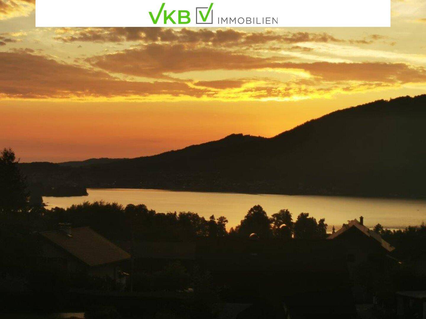 Malerischer Sonnenuntergang über dem See mit orangefarbenem Himmel und dunklen Silhouetten.