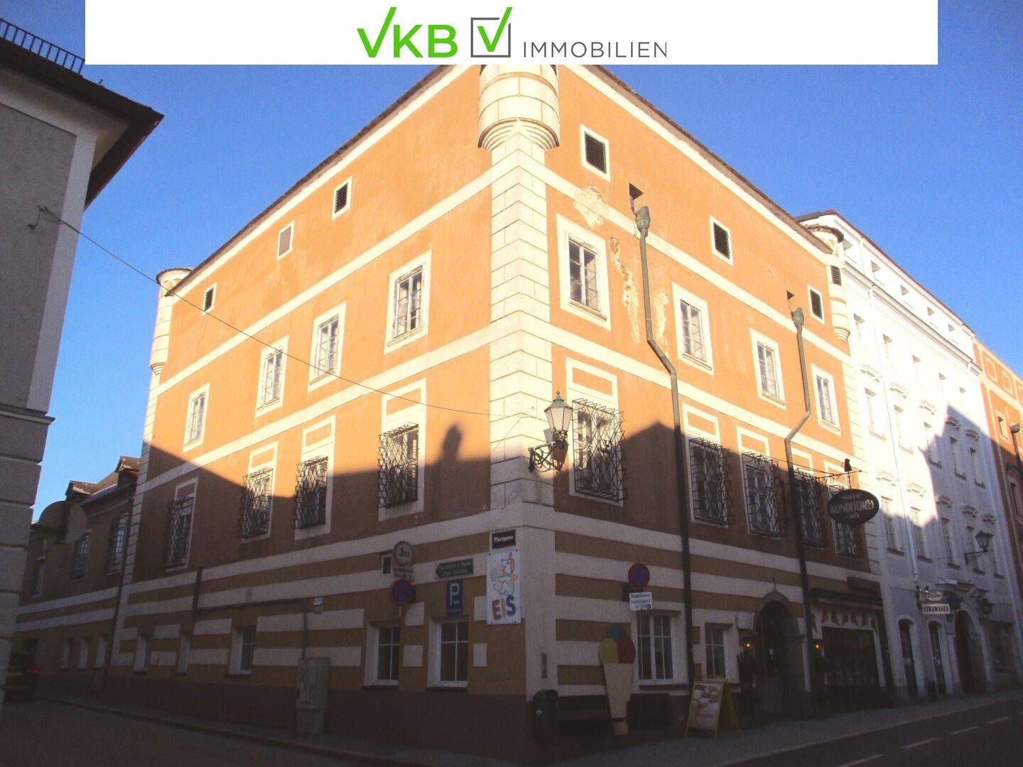 Historisches Eckgebäude mit markanter orange-weißer Fassade und traditioneller Architektur in der Stadt.