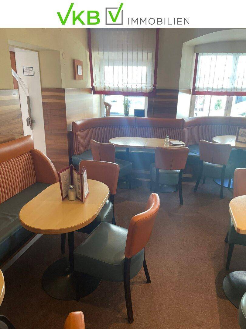 Gemütlicher Sitzbereich im Café mit gepolsterten Bänken und kleinen Tischen, ideal für Gäste.