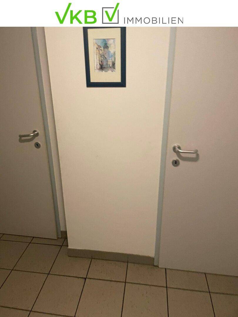 Schmaler Flur mit zwei Türen und einem kleinen gerahmten Bild an der Wand.