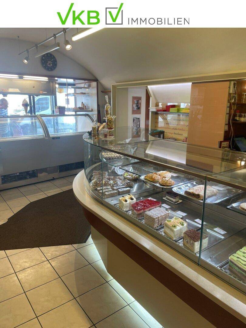 Innenansicht des Eiscafés mit einer gekrümmten Verkaufstheke, die eine Auswahl an Kuchen und Gebäck präsentiert.