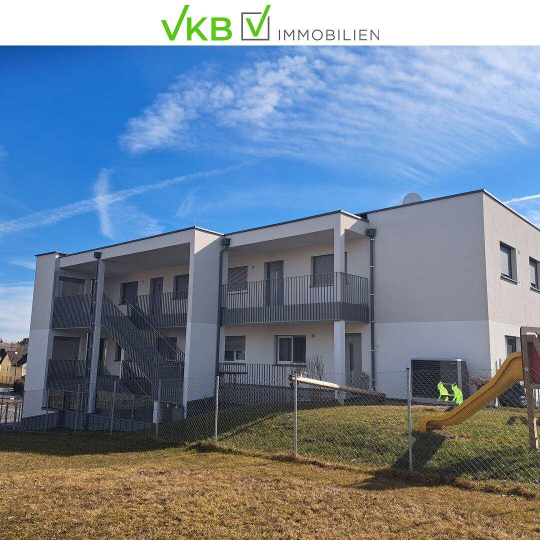 Moderne Wohnanlage mit Grünfläche und Kinderrutsche im Außenbereich.