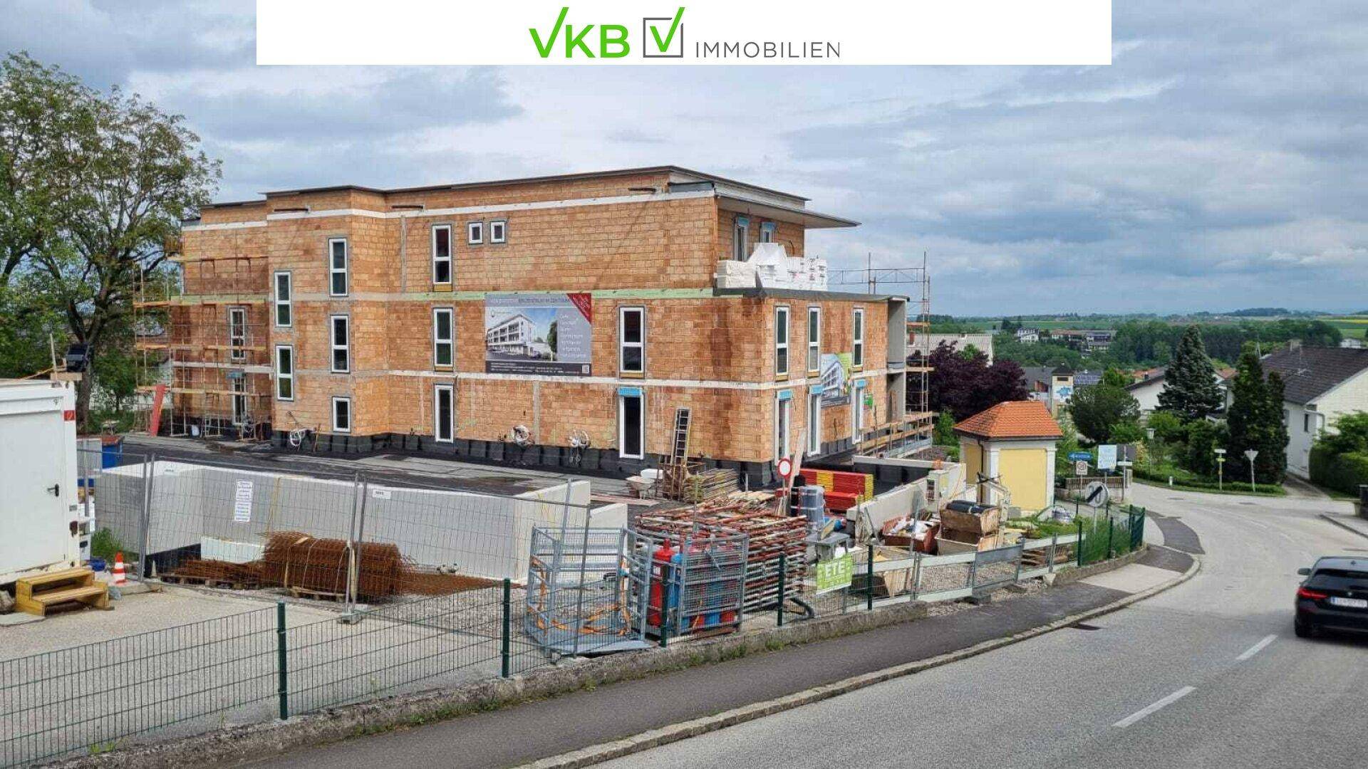 Baustelle einer modernen Wohnanlage mit Rohbau und Gerüst unter bewölktem Himmel.
