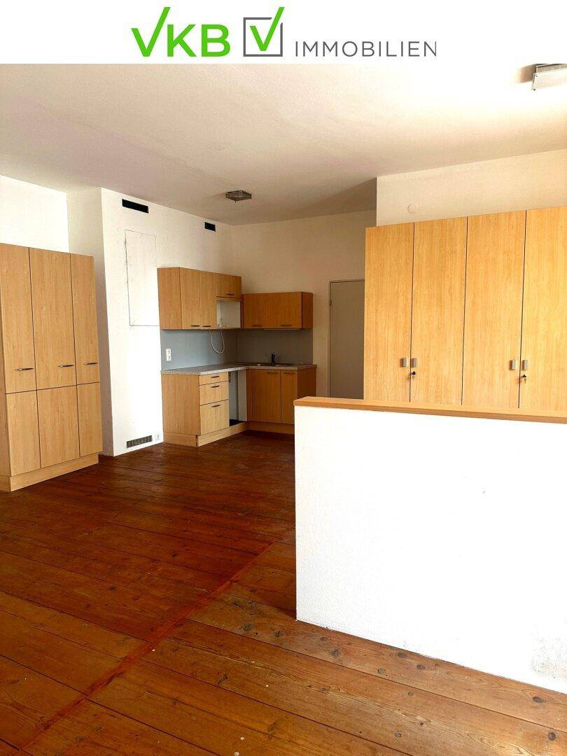 Heller Raum mit Holzdielenboden und einer funktionalen Küchenzeile mit Holzschränken.