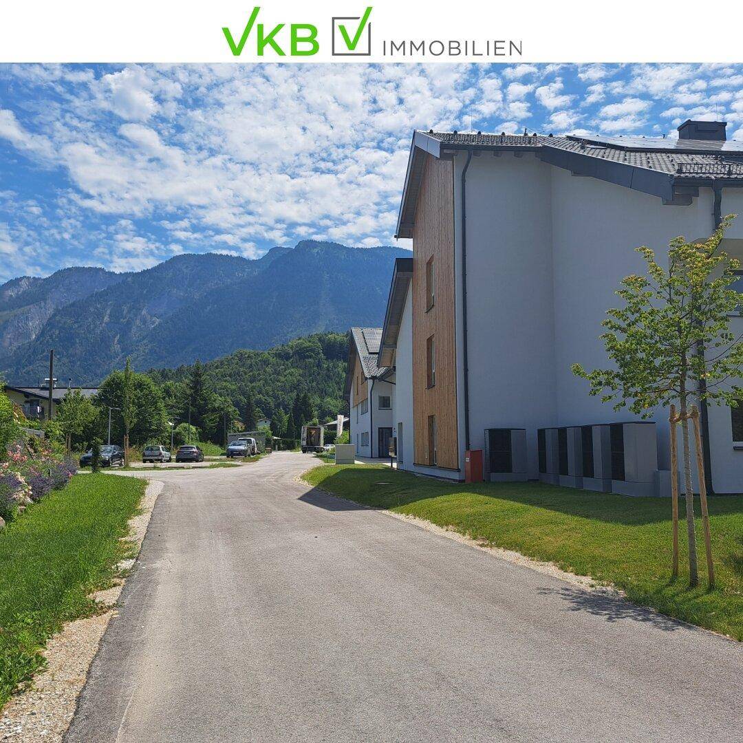 Ruhige Wohnstraße mit modernen Gebäuden und beeindruckendem Bergblick im Hintergrund.