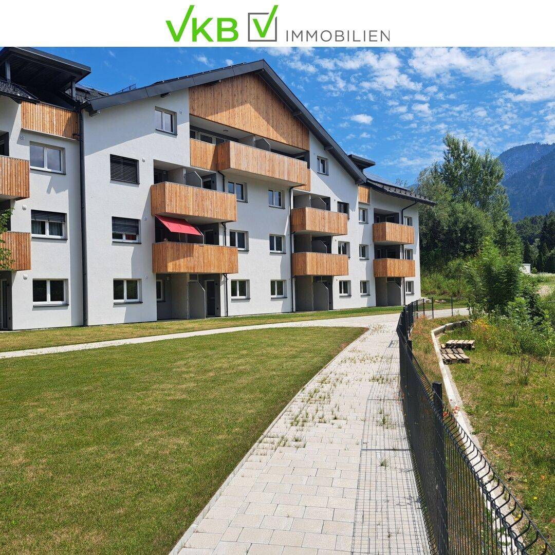 Attraktives Wohngebäude mit hellen Fassaden und Holz-Balkonen, umgeben von Grünflächen.