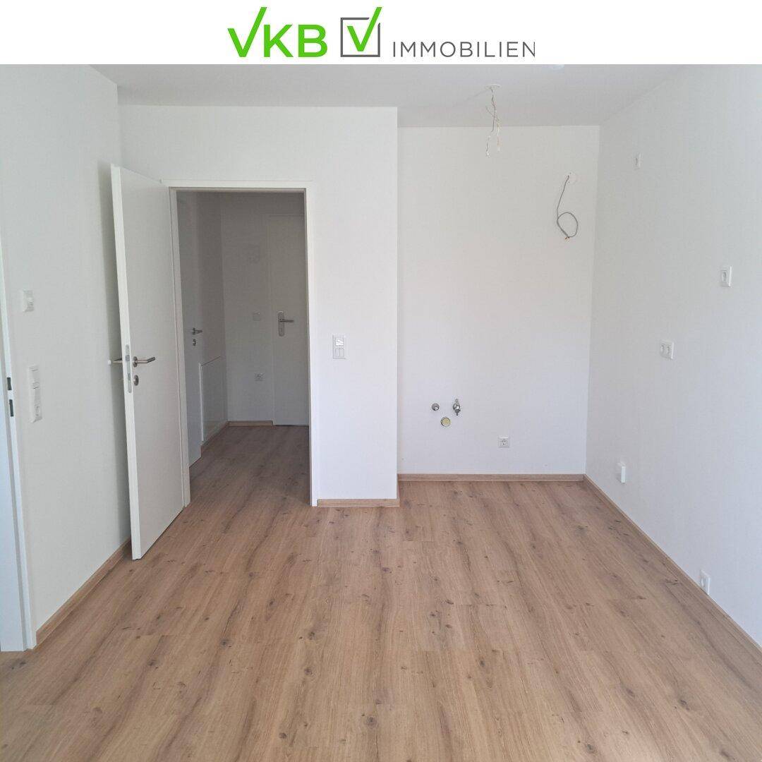 Leerer Raum mit hellem Laminatboden und weißen Wänden, bereit für die individuelle Gestaltung.