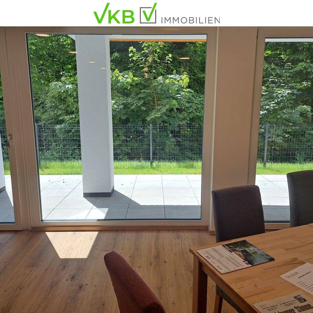 Heller Essbereich mit Holztisch und Zugang zur Terrasse, umgeben von viel Grün.
