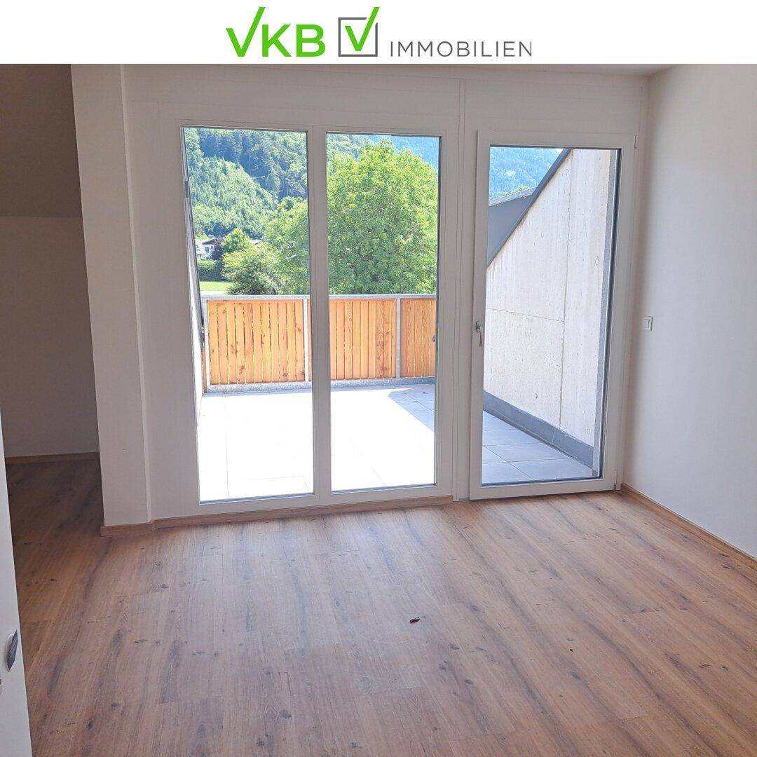 Heller Raum mit Holzboden und Zugang zu einem Balkon mit Bergblick.