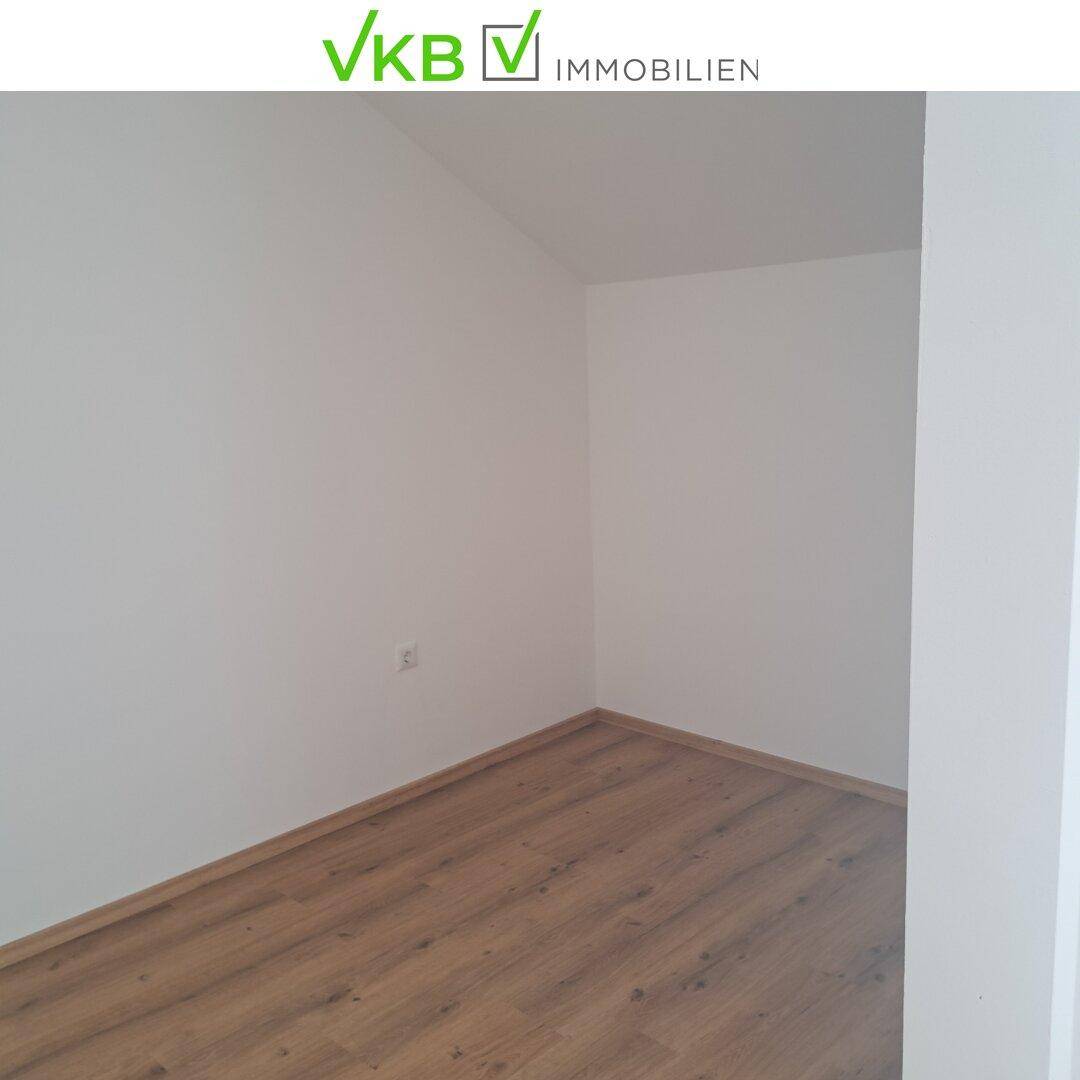 Heller, leerer Raum mit Laminatboden und weißen Wänden, bereit für individuelle Gestaltung.