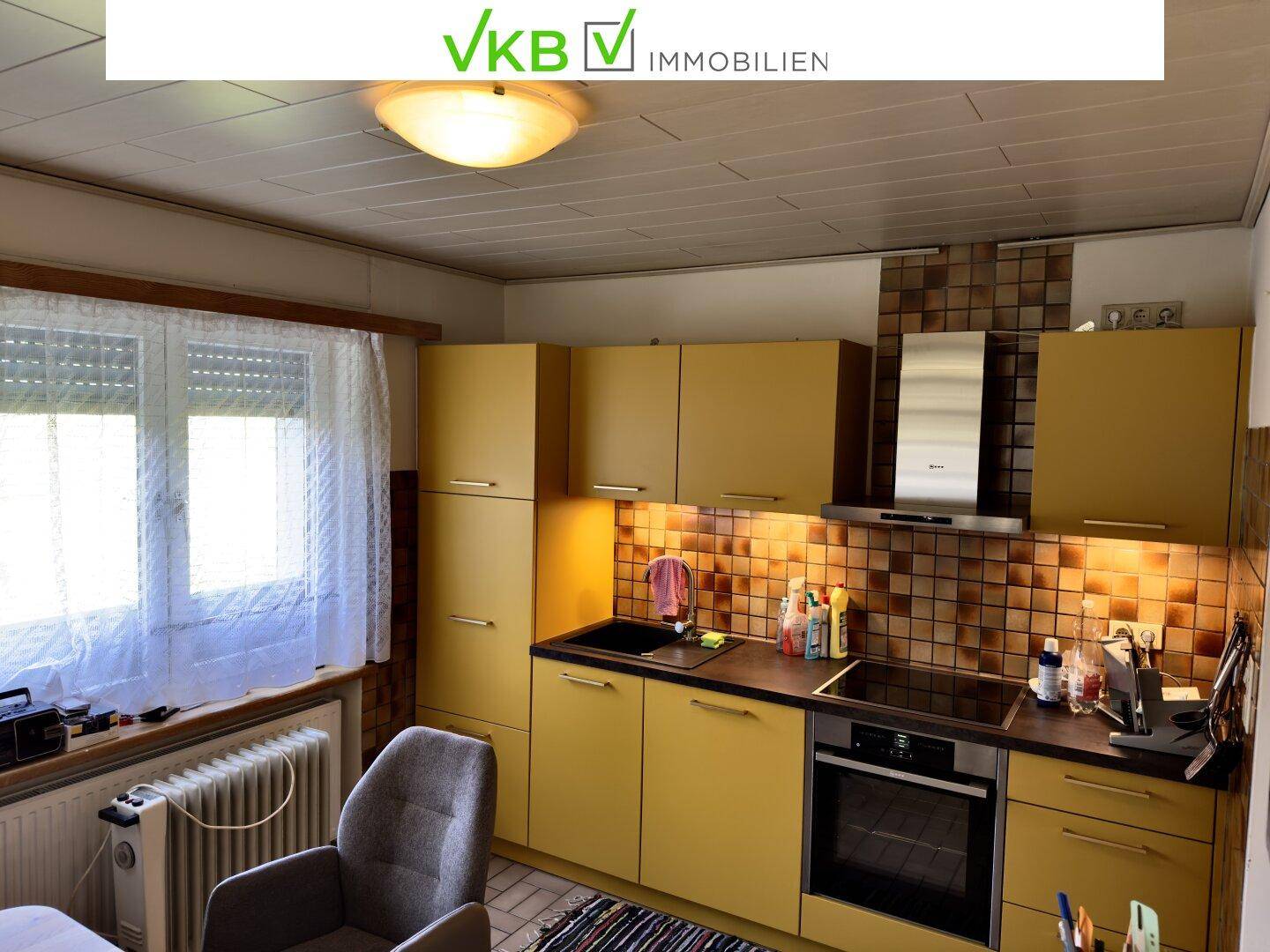 Funktionale Küche mit gelben Schränken, dunkler Arbeitsplatte und gefliestem Spritzschutz, inklusive Backofen.