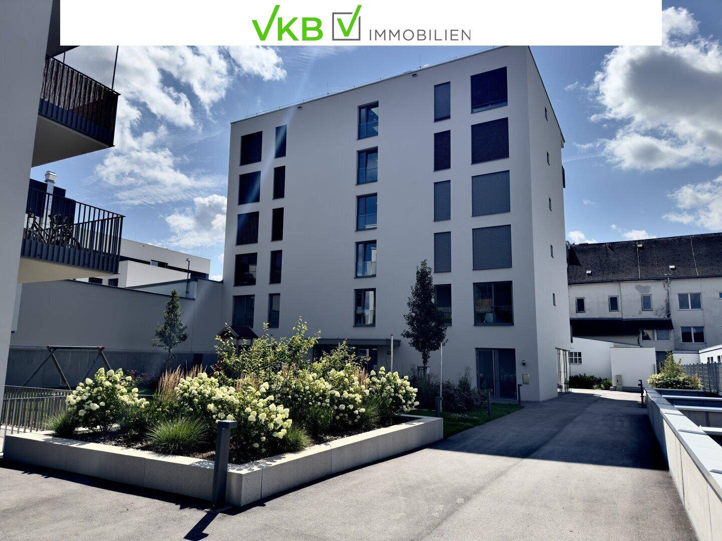 Modernes Mehrfamilienhaus mit schlichter Fassade und gepflegten Grünflächen im Außenbereich.