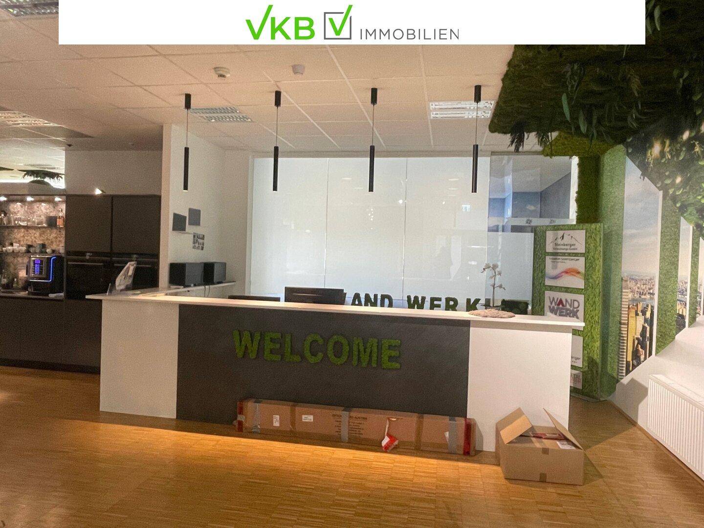 Detailansicht des Empfangstresens mit "Welcome"-Schriftzug und modernen Hängelampen über dem Schreibtisch.