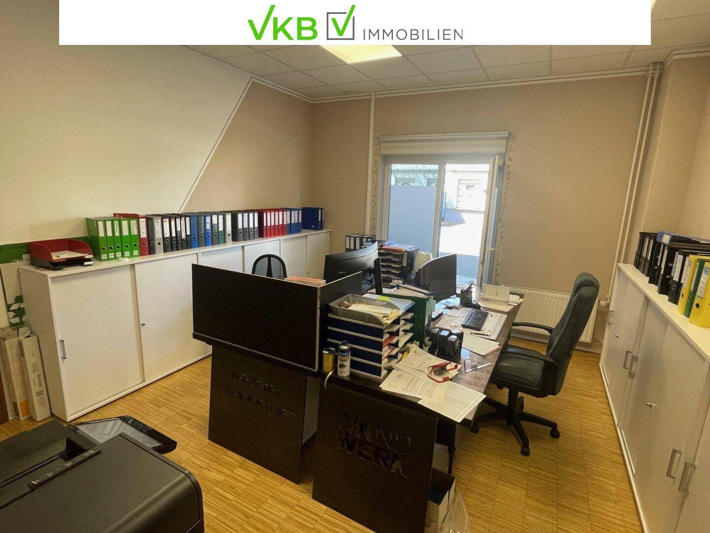 Funktionales Büro mit Schreibtisch, Bürostuhl, Computern und praktischen weißen Aktenschränken.