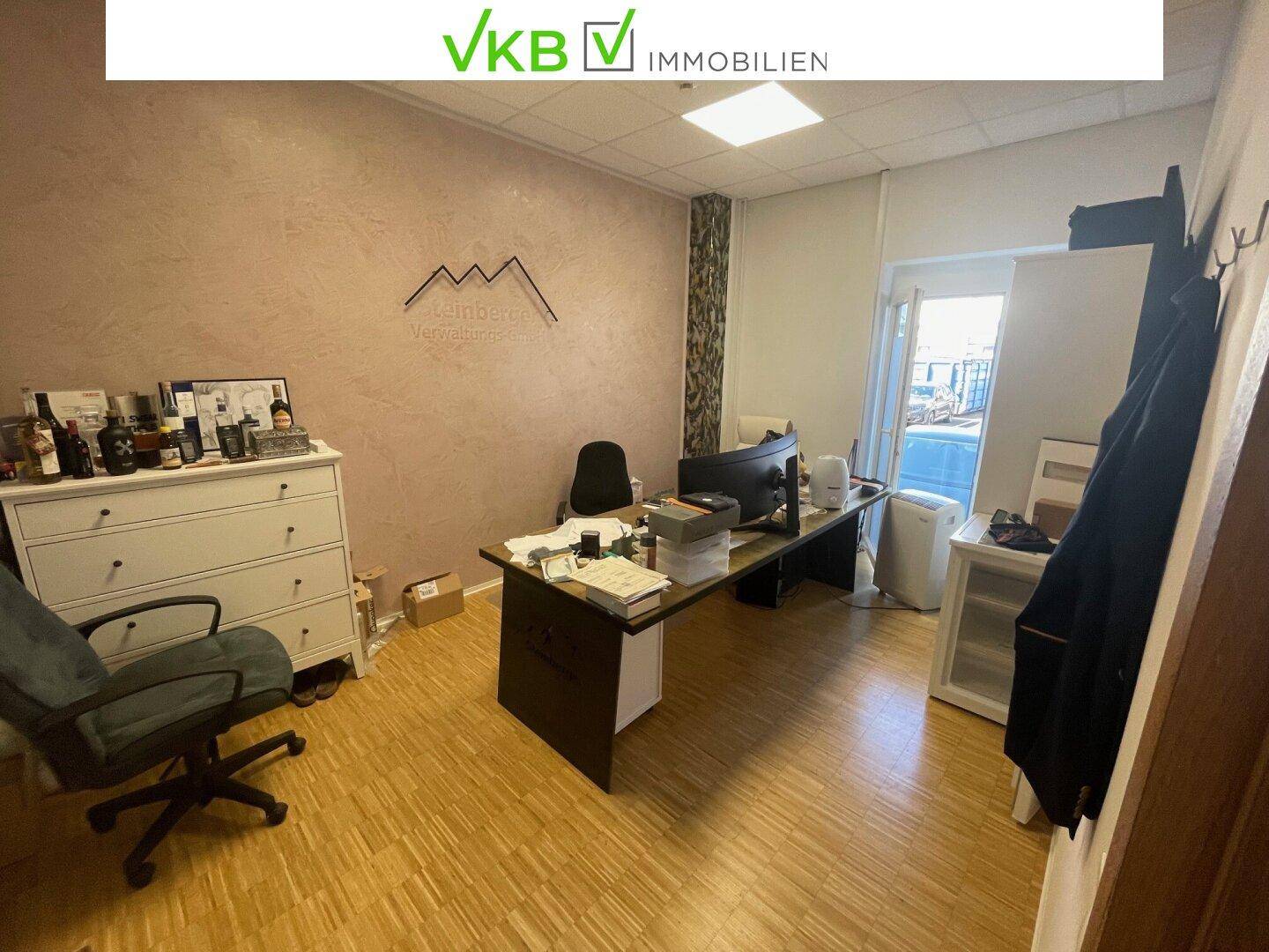 Modernes Büro mit großem Schreibtisch, Bürostuhl und einer Kommode, gut beleuchtet durch ein Fenster.