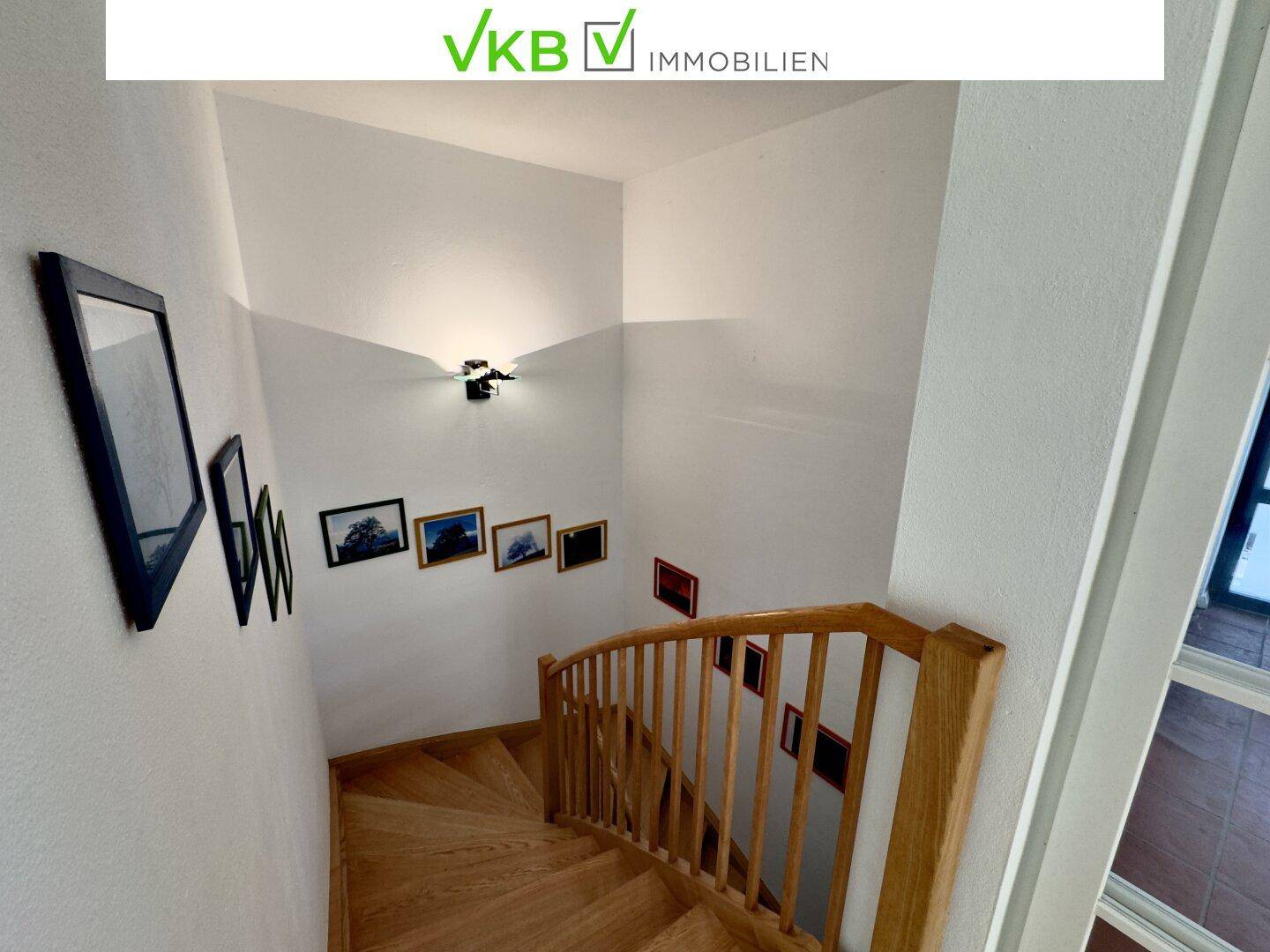 Holztreppe mit Geländer und Wanddekoration, die verschiedene Ebenen verbindet.