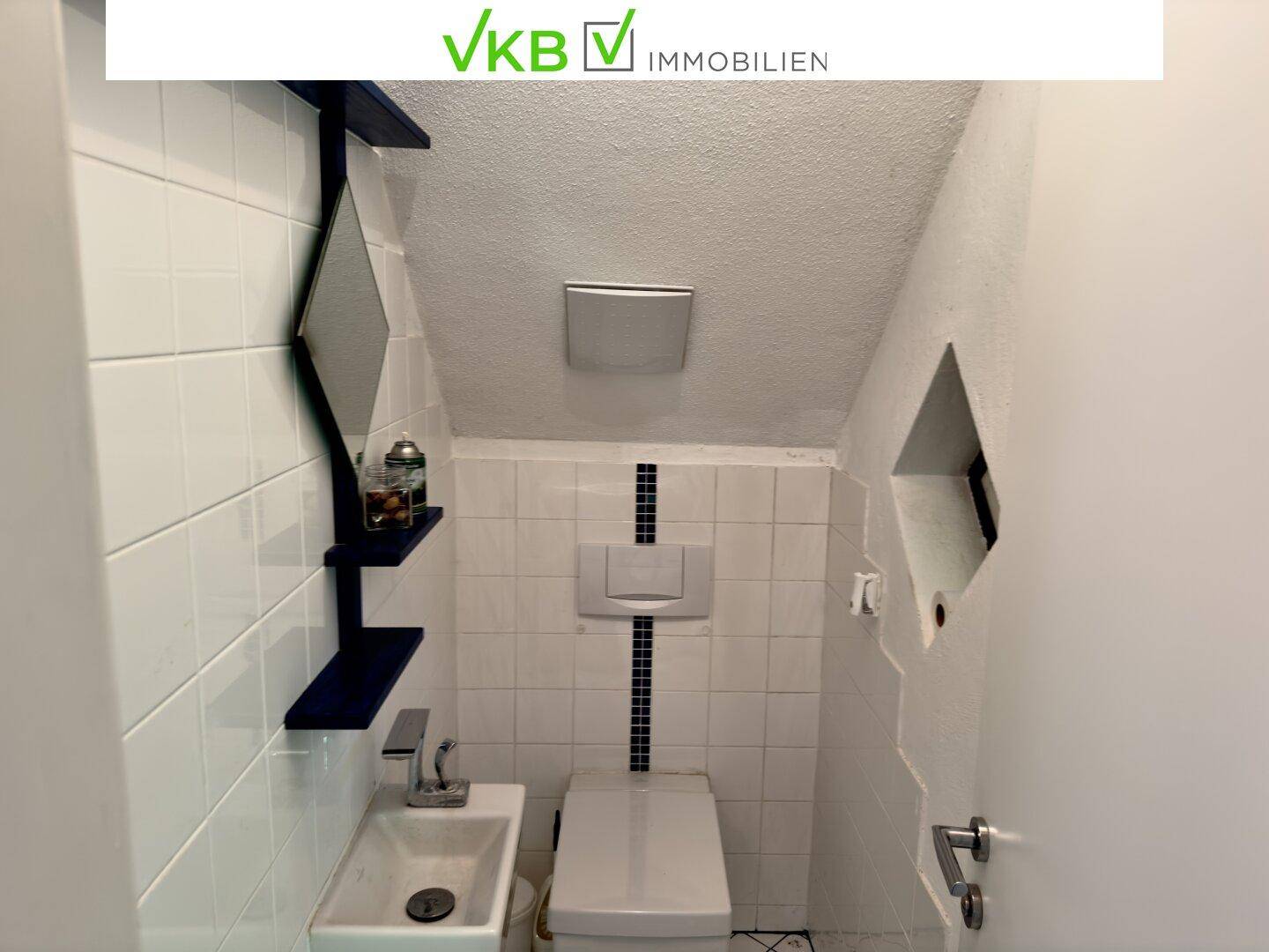 Kleines Gäste-WC mit Waschbecken, Toilette und weiß gefliesten Wänden.