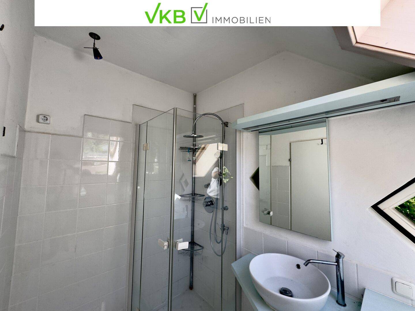 Modernes Badezimmer mit Duschkabine, Waschbecken und Dachschräge.