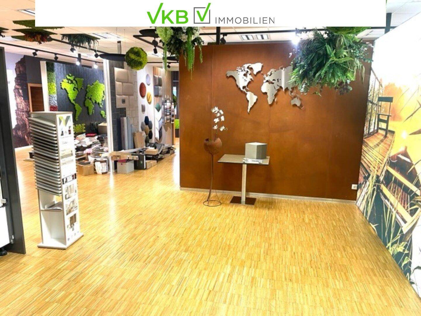 Heller Ausstellungsraum mit einer Weltkarte an der Wand, dekorativen Pflanzen und verschiedenen Präsentationselementen.