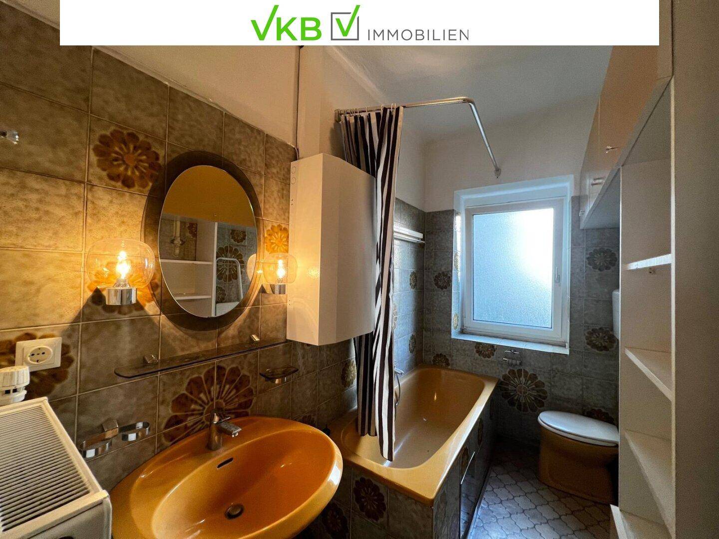Badezimmer im Stil der 80er Jahre mit orangefarbenen Fliesen, Badewanne und Fenster.