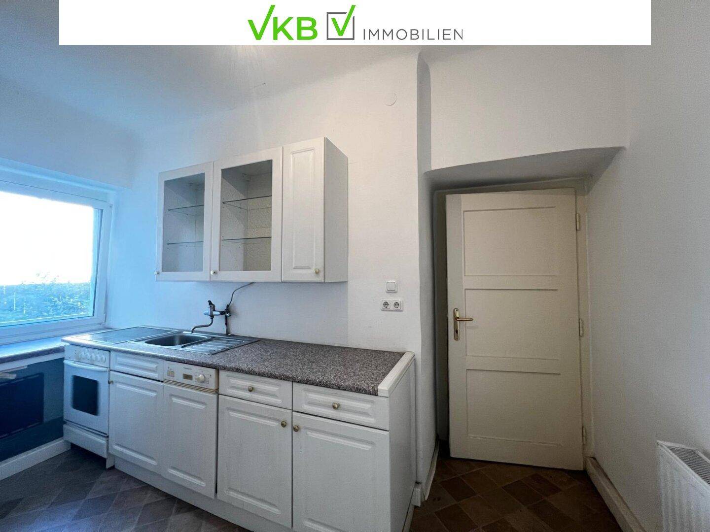 Funktionale Küche mit weißen Schränken, Spüle und Herd, bietet grundlegende Kochmöglichkeiten.