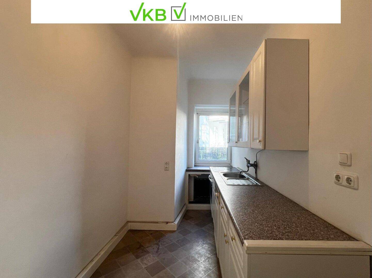 Kleine Küche mit weißen Unterschränken, Spüle und Fenster, ideal für eine Kochnische.
