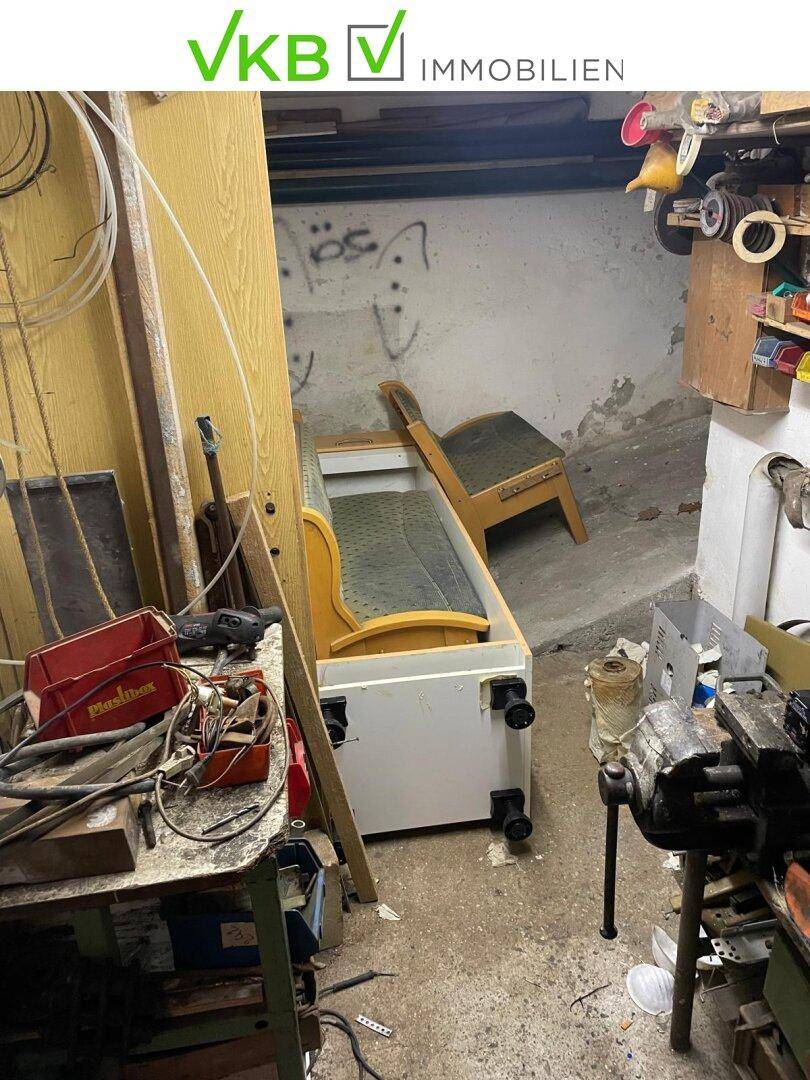 Unaufgeräumter Kellerraum, der als Werkstatt oder Abstellraum dient, mit verschiedenen Werkzeugen und Möbeln.