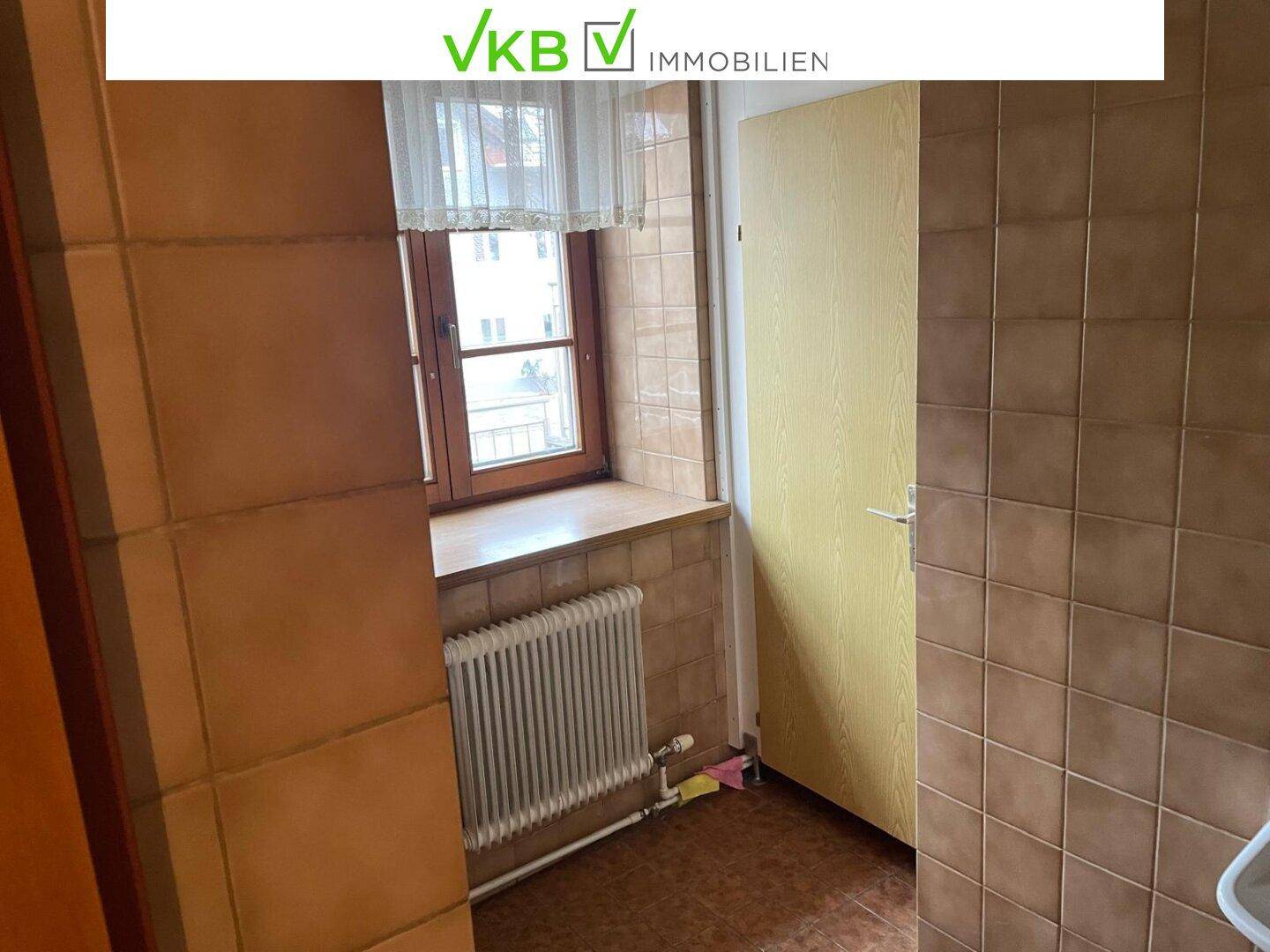 Kleiner gefliester Raum mit Fenster und Heizkörper, der als Abstellraum oder Waschküche dienen könnte.