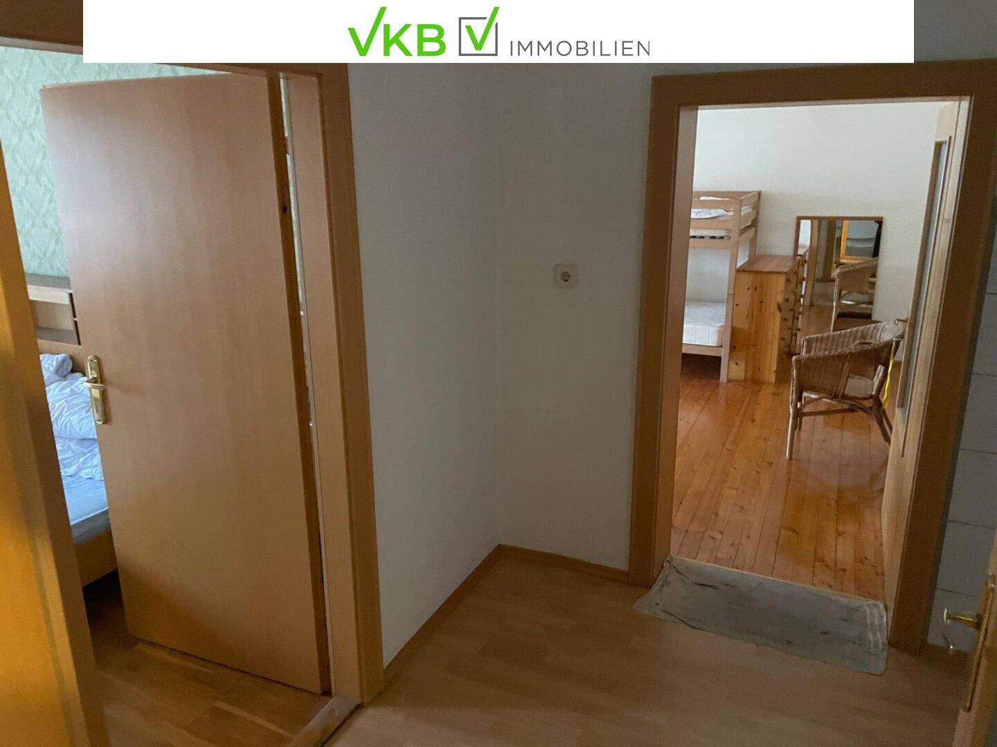 Flur mit Holzboden und Blick in ein Schlafzimmer mit Etagenbetten und weiteren Möbeln.